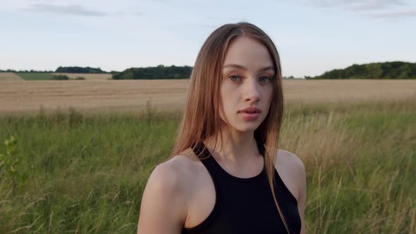 Portrait of Pretty Longhaired Young Sports Girl Looking at Camera at Field alt
