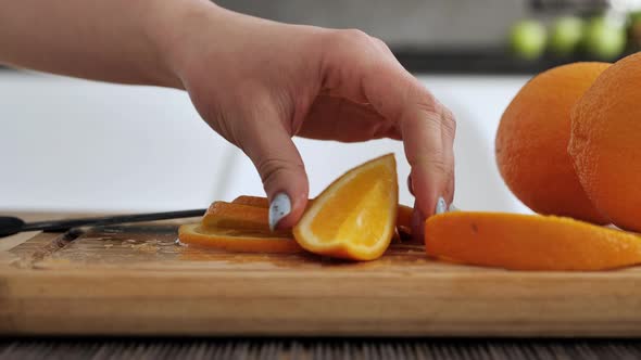 Women's Hands with a Knife Cutting Orange on the Cutting Board alt