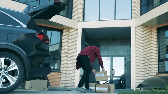 A Man Is Putting Together Parcels at the Doorstep of a Building alt