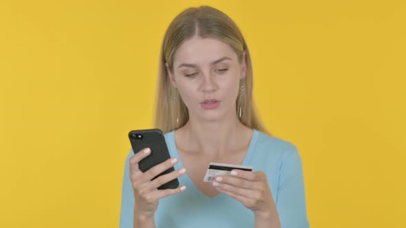 Young Woman Shopping Online via Smartphone on Yellow Background alt