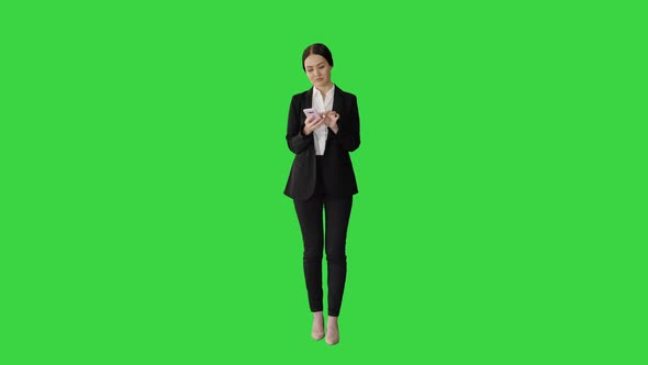 Casual Female in a Suit Texting on Her Phone on a Green Screen, Chroma Key. alt