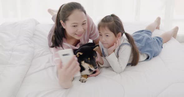 Mother and daughter playing with black dog on bed (12)