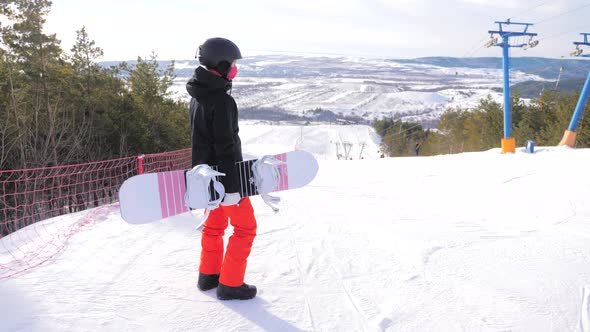 A Young Woman on a Snowboard on Top Mountain on a Ski Track alt