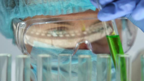 Lab Assistant Adding Green Liquid in Test Tube, Monitoring Chemical Reaction alt