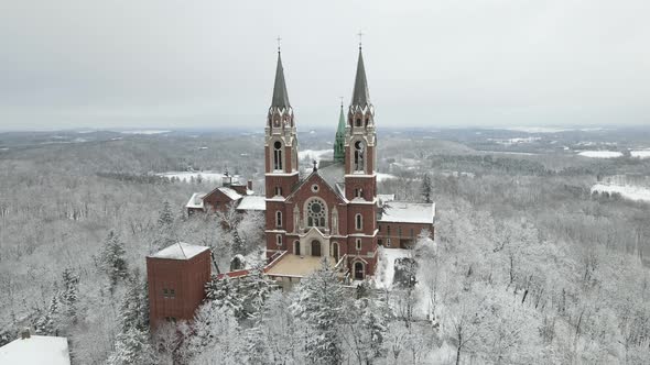 Drone view of church on mountain in Wisconsin. Snow covered mountain and forest.