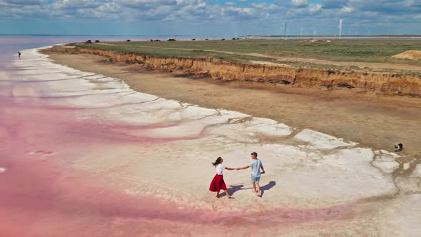 Lovely Young Couple Walking Along Beautiful Pink Lake with Salty Shore alt