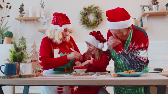 Funny Senior Grandparents and Granddaughter Playing with Flour Smearing on Face at Christmas Kitchen alt