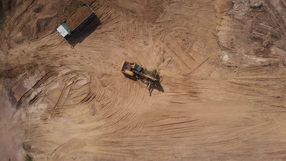 Aerial top view: yellow excavator moving broken tree.