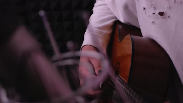 Handsome Man Plays Guitar and Sings Into Microphone in Recording Studio