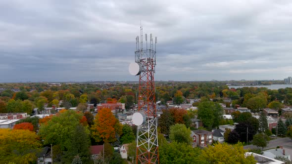 4K camera drone orbit around a cellular tower with autumn season colors in the background.