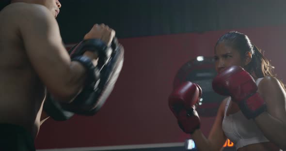 woman exercise with trainer at boxing gloves and self defense lesson punching alt