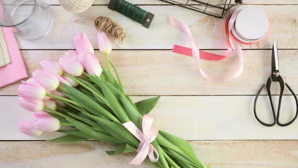 Step by step. Florist wrapping pink tulips in bouquet alt