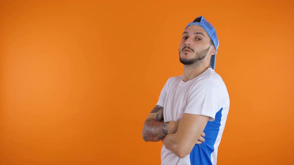 Football Fan Soccer Hooling with Crossed Arms Looking Serious, Isolated on Orange Background alt