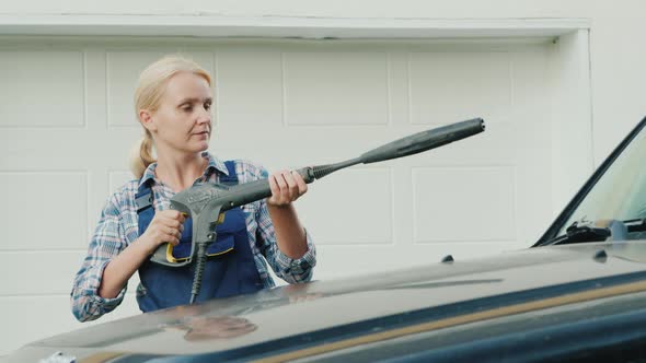 Portrait of an Active Woman Washing Her Car Near the Garage alt