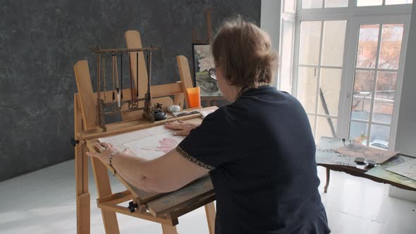 Senior Woman Artist Finishing Painting in Studio alt
