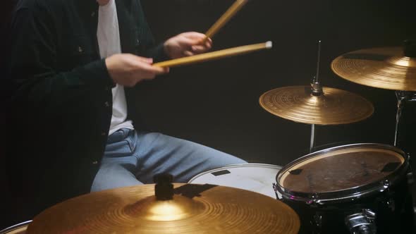 Drummer Playing the Drum Set in a Dark Room on a Black Background alt
