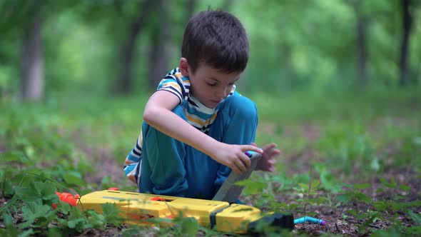 A Boy Loads a Clip with Cartridges From a Toy Machine Gun Outdoors alt
