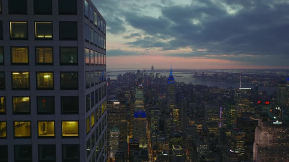 Tight Fly Above Top Storeys of Modern Skyscraper Towering Above City alt