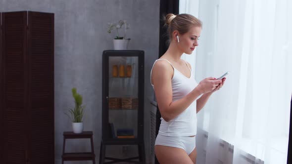 Young  girl is standing in front of the window alt