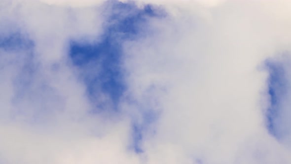 Solid White Dense Smoke Against a Blue Sky As Swift Cumulus Clouds alt