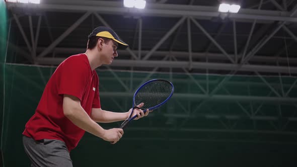 Adult Tennis Player is Training in Indoor Court Medium Shot of Man with Racquet Striking Ball Slow alt
