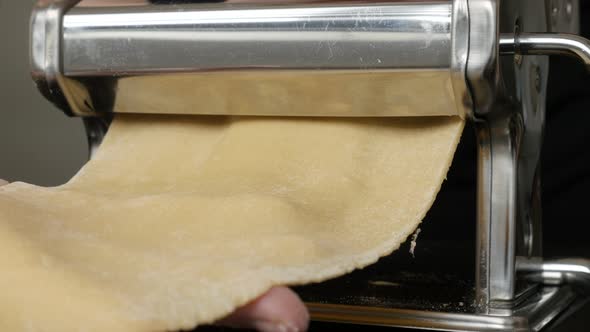 Processing dough for Italian lasagna 4K 2160p 30fps UltraHD footage - Metal pasta machine used at ho alt