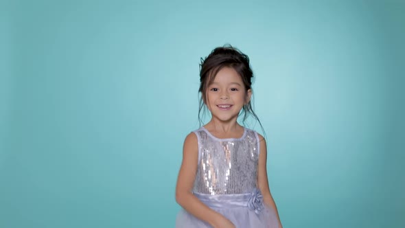 Beautiful Little Child Girl in Silver Dress Dancing on Blue Background