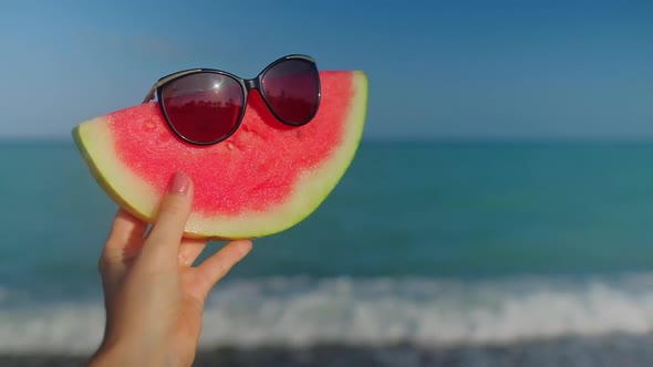 A Hand Holding a Watermelon with Sunglasses