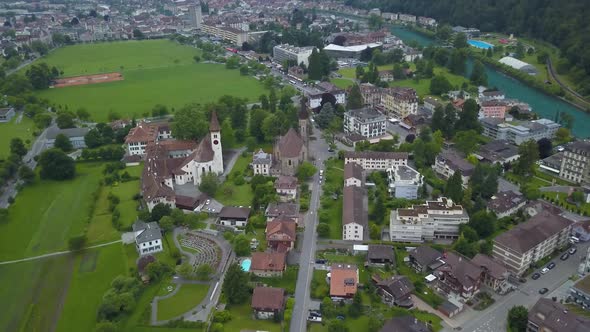 Aerial lowering on Catholic and Protestant Churches in Interlaken town valley next to lake, surround alt