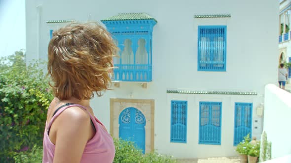 a Tourist in a Protective Mask and a Summer Dress Walking Through the Ancient City to Take a Photo alt