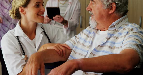 Female doctor kneeling while talking to disabled senior man on wheelchair 4k alt