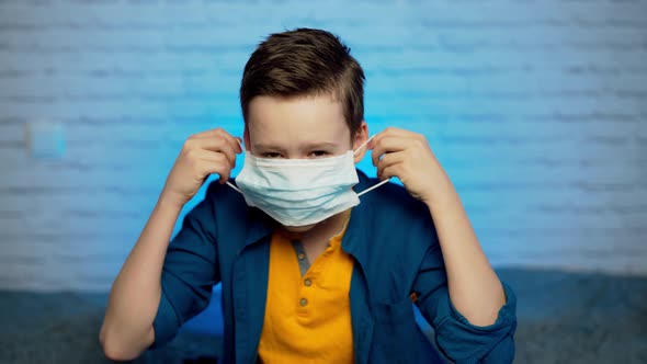 Beautiful boy puts on face medical mask against bacteria and viruses alt