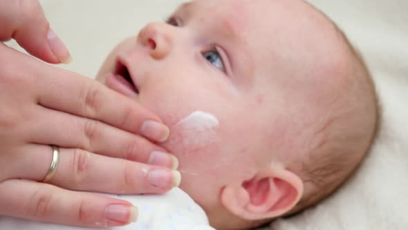 Closeup of Mother's Hand Applying Moisturizing Medical Lotion on Skin of Her Little Baby Suffering alt