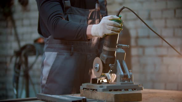 Young Man Using a Grinder To Make Notches on the Metal Detail - Sparks Comes Off the Blade alt