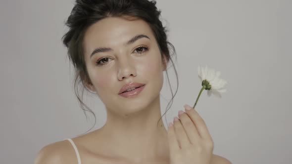 Pretty Girl with Clean Skin Touching Her Face with Fresh White Flower alt