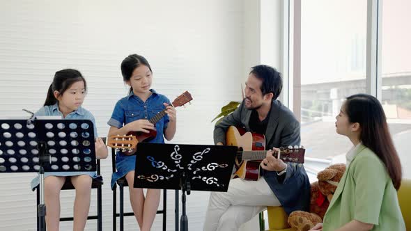 in a music school class, a music teacher is teaching children in a music school to learn guitar chor