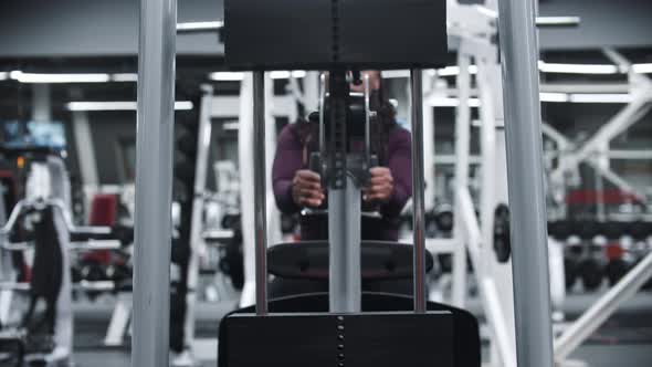 A Black Woman Working Out in a Gym  Training Hands on a Exercise Equipment with Weights alt