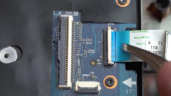 Connecting a Ribbon Cable to the Laptop Motherboard with Tweezers Laptop Repair in a Service Center alt
