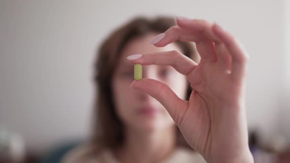 A Tablet in the Hands of a Woman at Close Up. The Girl Looks at the Medicine in Her Hand. Dose of
