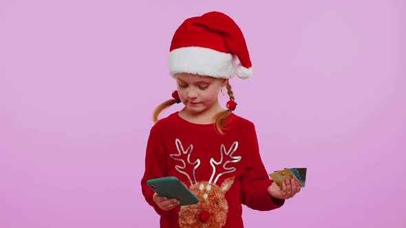 Girl in Christmas Sweater Using Credit Bank Card Smartphone While Transferring Money Shopping Online alt
