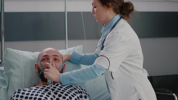 Close Up of Sick Man Patient Resting in Bed While Doctor Putting Oxygen Mask alt