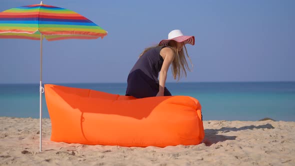 Young Woman on a Tropical Beach Laying Down on an Inflatable Sofa. Summer Vacation Concept alt