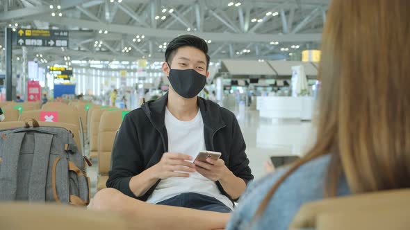 friends asian tourist traveller wear protective face mask  have conversation wait flight schedule alt