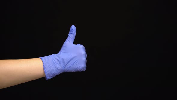 Female Hand in a Latex Medical Glove Makes an Like Gesture Isolated on Black Background alt