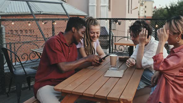 Four Diverse Friends Laughing at Outdoor Cafe alt