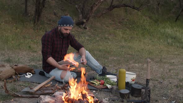 Traveler Man Sitting Near Campfire and Reading Book