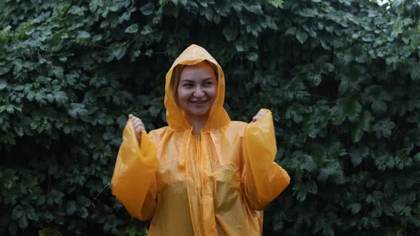 An Attractive Girl Rejoices in the Rain in the Park in the Yellow Pasha