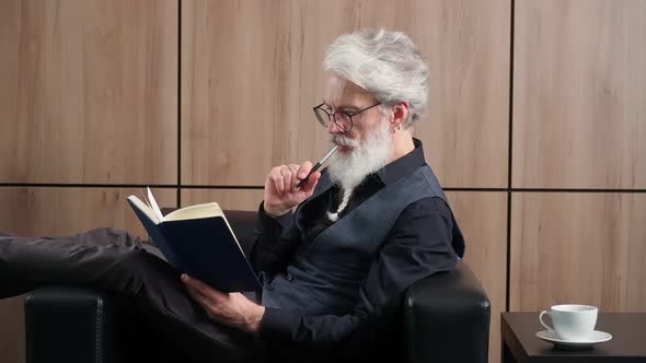 Elegant Grayhaired Man Works in the Office Art Director Writes Down Ideas and Concepts in a Notebook alt