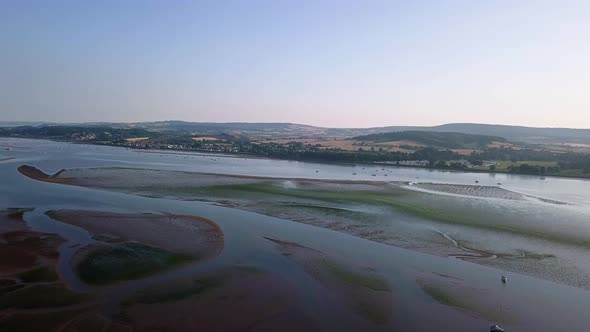 Flying over the ocean off of the shores of an historical town in southwest England. The water is cal alt