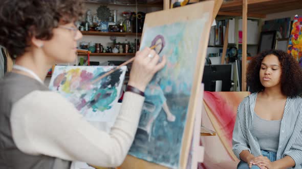 Female Artist Painting Portrait of Afro-American Model Creating Beautiful Colorful Picture alt